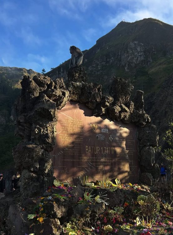 The Batur 1717 m shrine marker near the summit, with a long-tailed macaque sitting on top of it